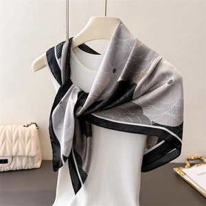 Detailed texture of black and white floral satin scarf tied on a white vest
