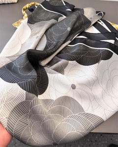 Detailed texture of satin floral scarf with elegant wavy patterns and black piping