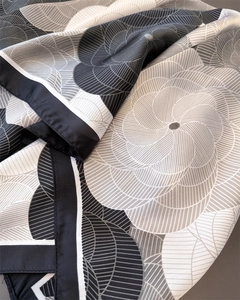 Detailed close-up of premium satin scarf featuring abstract geometric spiral patterns
