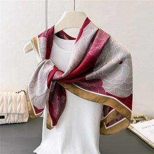 Close-up of elegant floral silk scarf styled with gold tray and a white quilted handbag