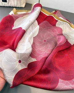 Detail of elegant satin floral scarf showing smooth texture and red spiral geometric patterns