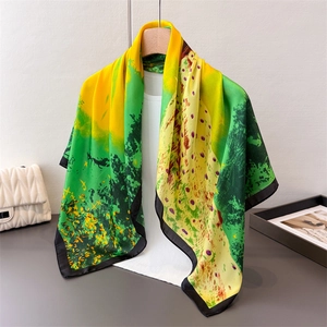 Elegant satin peacock print scarf with green forest pattern on a wooden hanger