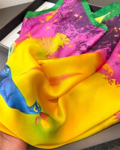 Detailed view of peacock print satin scarf with vibrant magenta and yellow silk folds