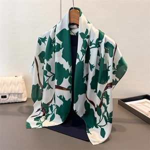Detail eines Satin-Halstuchs mit dunkelgrünen Blumen und Beauty-Schleife auf einem Kleiderbügel