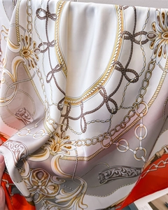 Detail of luxury satin silk scarf featuring golden chain print and orange border