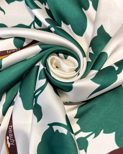 Nahaufnahme des elfenbeinfarbenen Seidenschals mit Satin-Textur und Blattmustern