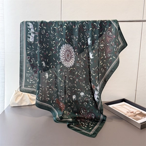 Deep green satin silk scarf featuring elephant print and mandala patterns on a metal hanger