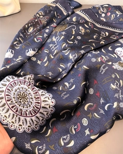 Close-up of silk-satin scarf texture with dark blue mandala and letter patterns