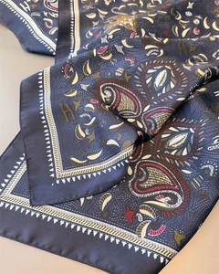 Close-up of luxury satin silk scarf with navy blue paisley and H-letter pattern