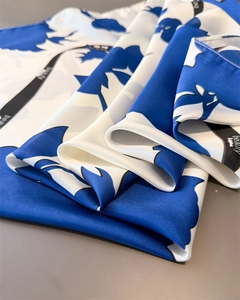 Nahaufnahme eines blau-weißen Seidenschals mit Blumenmuster und schwarzem Beauty-Aufdruck