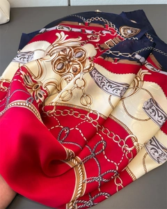 Detail view of luxurious satin scarf with vintage gold chain and buckle patterns