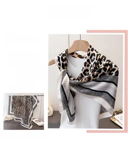 Détail d'un foulard en soie synthétique avec motif léopard et bordures dorées élégantes