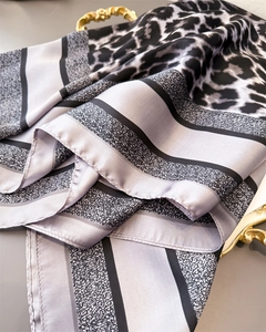 Détail d'un foulard en soie avec imprimé léopard, rayures et finition de bord roulé