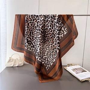 Grand foulard carré élégant en soie à imprimé léopard présenté avec sac à perles