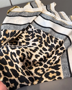 Détail d'un foulard de luxe en soie synthétique avec imprimé léopard et motifs géométriques