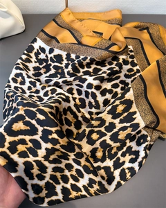 Vue détaillée d'un foulard en soie léopard avec bordures dorées et éclat satiné luxueux