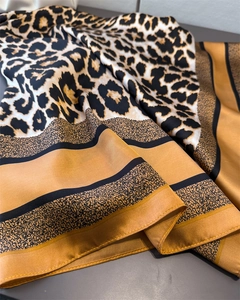 Gros plan d'un foulard en soie léopard avec texture lisse et bordure jaune doré