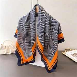 Detail van zijdeachtige sjaal met houndstooth print en oranje contrastranden op hanger