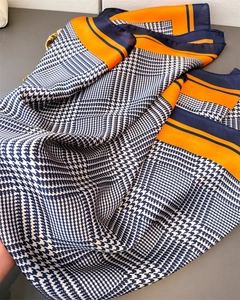 Detail van zijdeachtige sjaal met pied-de-poule patroon en oranje-marineblauwe randen