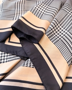 Detailopname van een zijden sjaal met houndstooth-patroon en satijnen glans