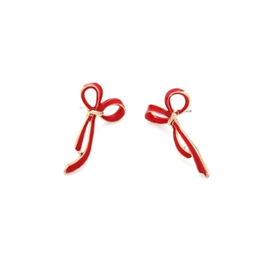 Dettaglio orecchini a fiocco in smalto rosso con eleganti bordi in metallo dorato