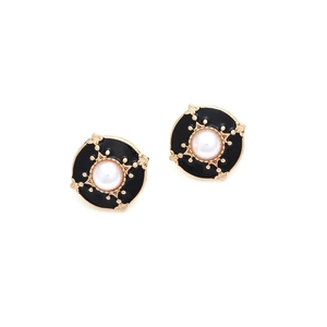 Close-up of vintage button earrings with black enamel, gold trim and white pearl center