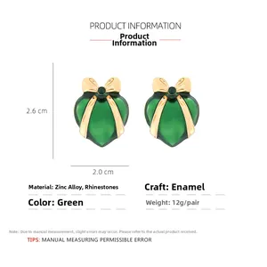 Detailed specs of green enamel heart earrings with gold bows and crystal inlays