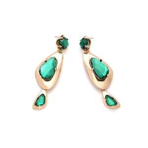 Close-up of gold drop earrings with emerald green geometric stones in a tiered design