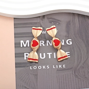 Détail de boucles d'oreilles en alliage en forme de bonbon avec motif de cœur en émail rouge
