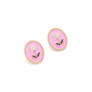 Close-up of oval retro earrings with pink enamel, white flower, and gold woven border