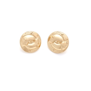 Macro detail of vintage gold-plated round earrings featuring embossed Pisces fish pattern