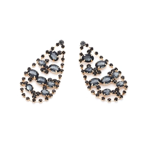 Détail de boucles d'oreilles goutte avec monture dorée et cristaux gris foncé brillants