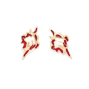 Irregular textured gold earrings with red enamel drip design on a clean white backdrop