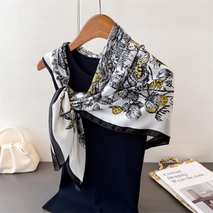 Élégant foulard en soie avec imprimé papillon noir et blanc sur un cintre en bois