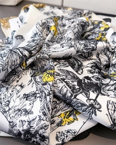 Détail d'un foulard en soie montrant des imprimés floraux et des papillons jaunes