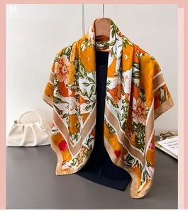 Detail of silk-like scarf with large orange floral print and champagne border on hanger