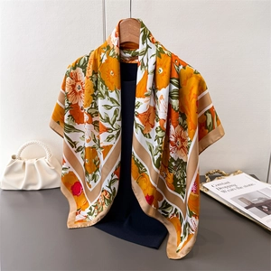 Detailed macro view of high-end silk scarf with orange flower print and golden edges