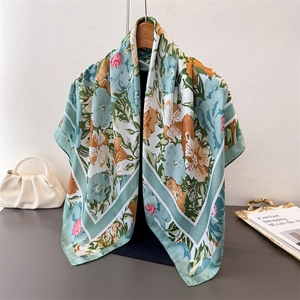 Close-up of floral silk scarf in sage green with elegant flowers on a hanger