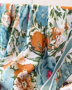 Detail of silk satin scarf showing large floral prints and dark green striped edges