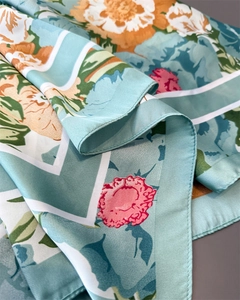 Close-up of mint silk scarf with floral print showing hem details and smooth satin texture