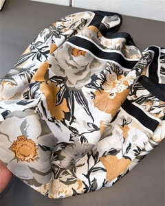 Detail of floral print silk scarf featuring elegant mustard yellow and grey patterns