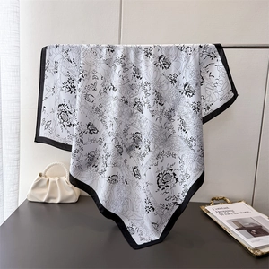 Elegant black and white floral silk square scarf displayed on a minimalist metal rack