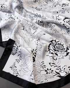 Macro view of floral ink print silk scarf showing smooth texture and detailed black borders