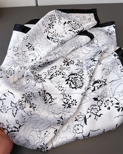Detail of floral pattern on black and white silk scarf with satin texture and border