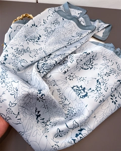 Close-up of elegant faux silk scarf with navy blue floral print and smooth satin texture