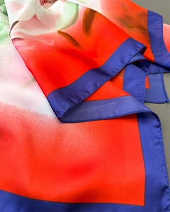 Close-up of silk scarf showing red floral pattern with neat blue stitched edges