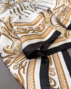 Detailed close-up of Baroque pattern silk scarf with golden scrolls and elegant folds