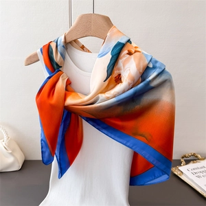 Detailed view of floral silk scarf with orange and blue peony prints on a hanger
