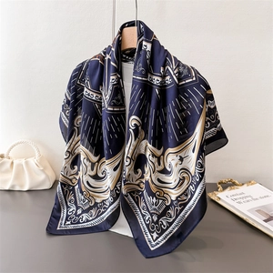 Luxurious navy blue silk-like square scarf with gold baroque floral pattern on a table