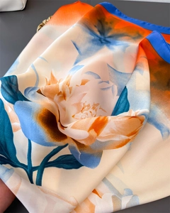 Detail of silk-satin scarf featuring orange peony patterns and blue border finish